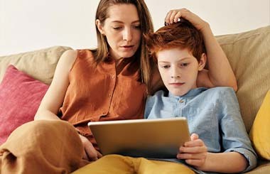 A woman sits with a boy on a sofa