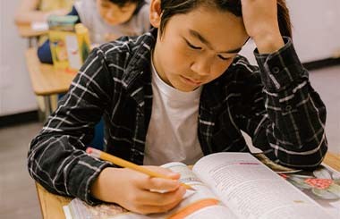 A boy is sat at a school desk working