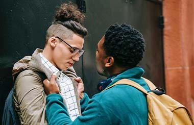 A boy holds another boy by his coat