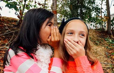 A girl whispers in the ear of another girl