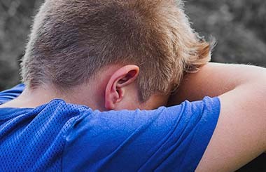 A boy with his head in his hands