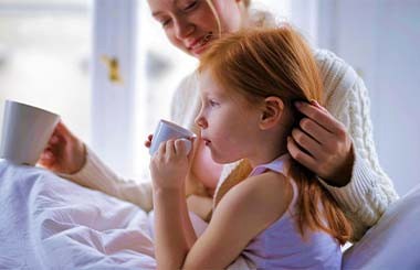 A woman and girl drinking from mugs