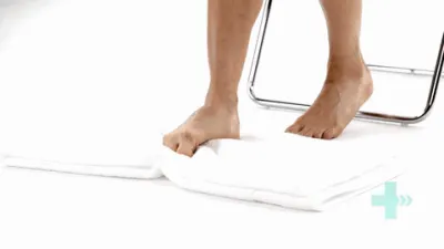 Moving image of someone sat with their foot on a towel, scrunching up their toes