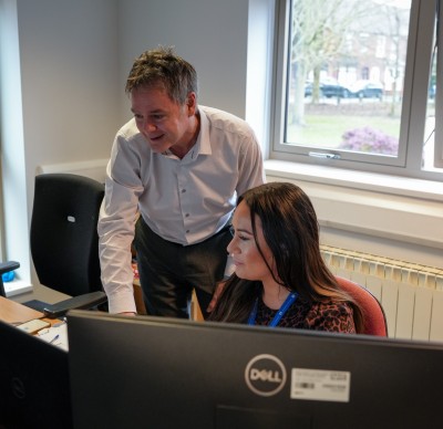 A man and a woman are looking at a computer monitor