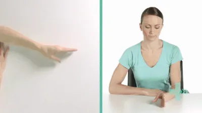 Moving image of someone sat down with their hand on a table. They are rotating their thumb in a circle