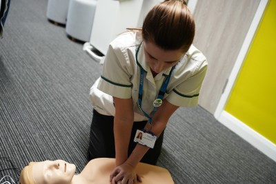 An occupational therapist is being trained how to deliver CPR on a dummy.