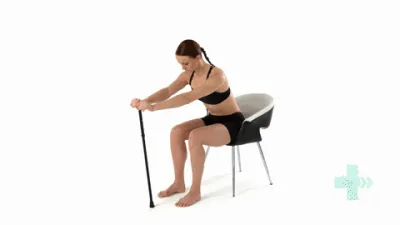 Moving image of someone sat on a chair with their hands on top of a stick and leaning forwards.