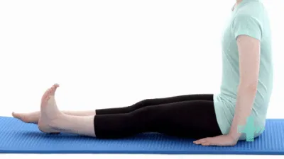 Moving image of someone sat on the floor with their legs out in front of them. They are tensing their muscles to push their knee into the floor